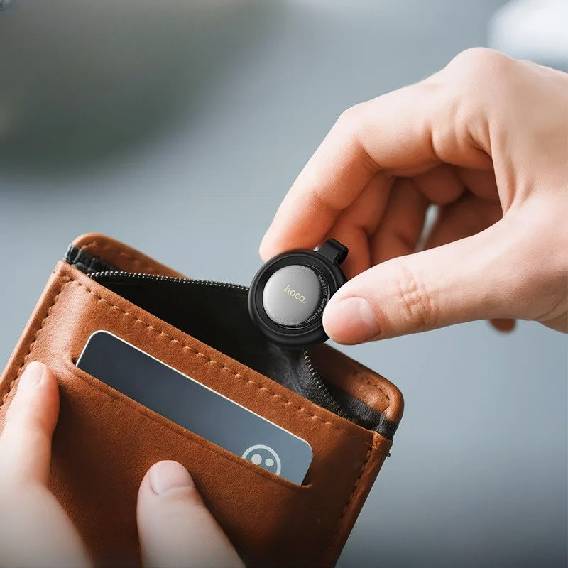 Hand placing a black device into a brown wallet with a blurred background