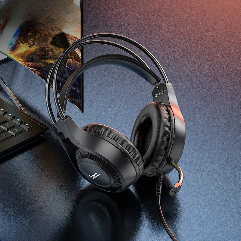 Black headphones on a desk with a blurred computer monitor in the background