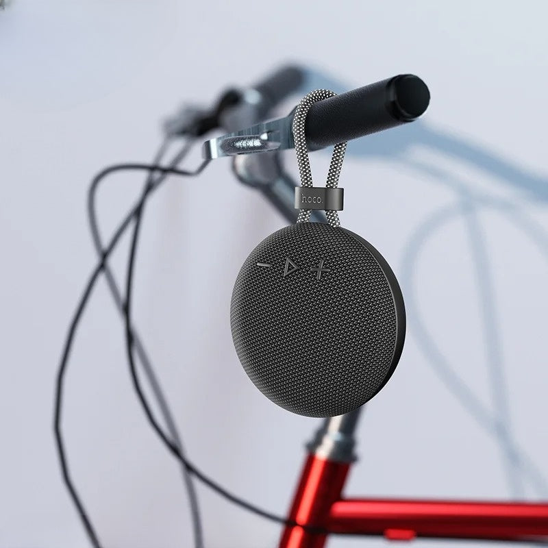 Black portable speaker attached to a bicycle with a blurred background