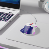 Gaming mouse on a desk with a laptop and headphones in the background