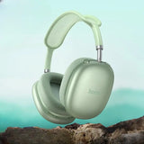 Light green headphones with 'hoco' branding on a blurred natural background