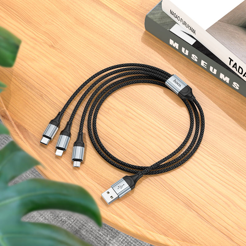 Multi-device charging cable on a wooden surface with books in the background